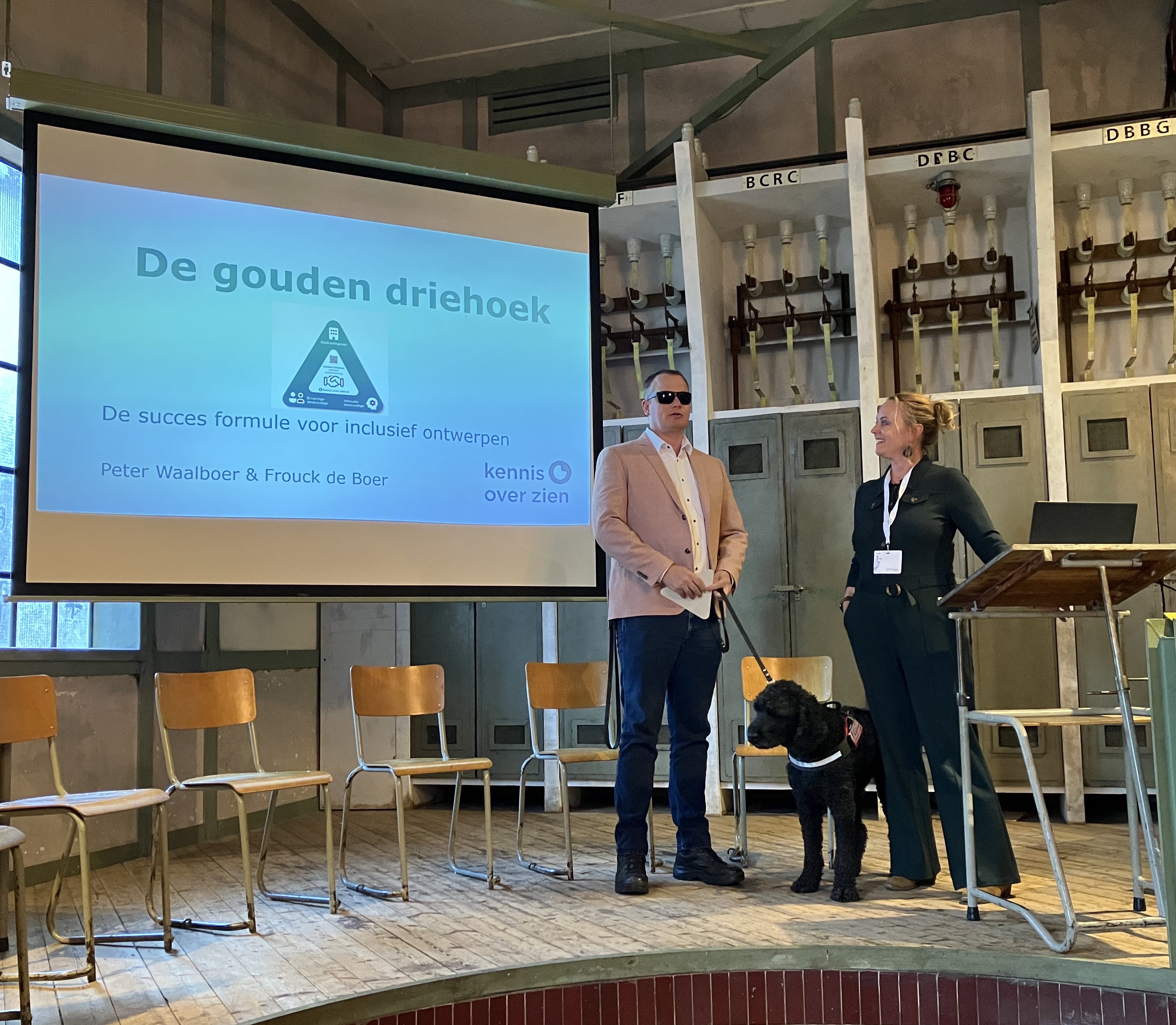 Frouck de Boer en Peter Waalboer geven een presentatie over de Gouden Driehoek. Ze staan op een podium voor een beamer met powerpoint slides.