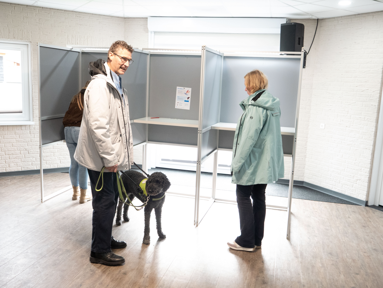 Ton en Hanneke de Boer en geleidehond Sofie bij een stemhokje