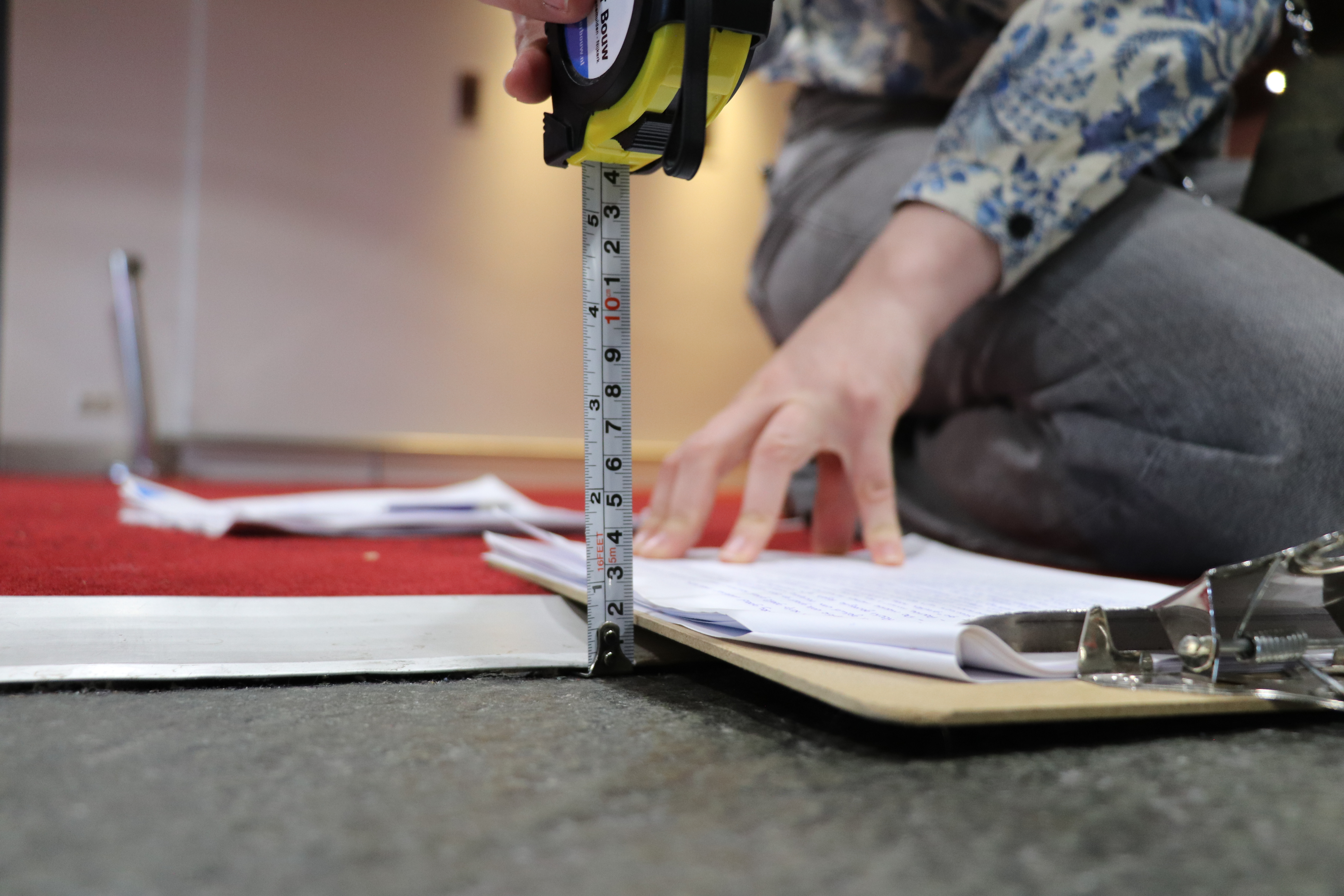 Gebruikersonderzoeker buigt zich over een aluminium strip die de overgang vormt tussen een donkere en een lichte vloer, terwijl ze de bruikbaarheid van de gidslijnen onderzoekt.