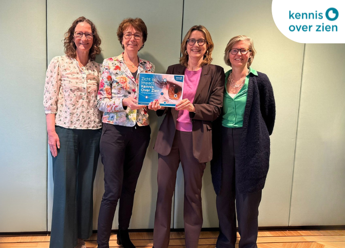 Foto van de overhandiging van de voortgangsrapportage. Vier vrouwen houden de voortgangsrapportage vast en poseren voor de foto.