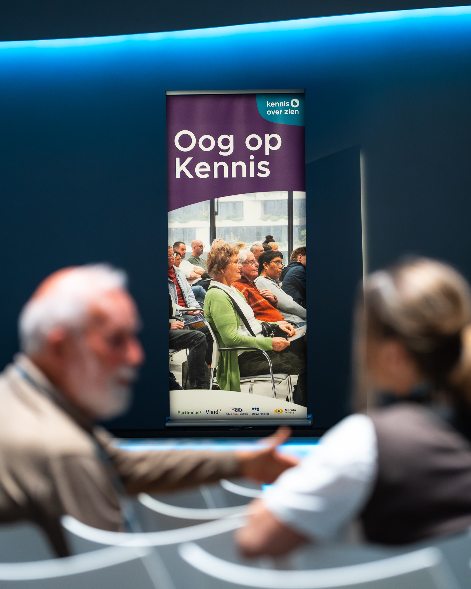 Oog op Kennis-banner met bezoekers op de voorgrond
