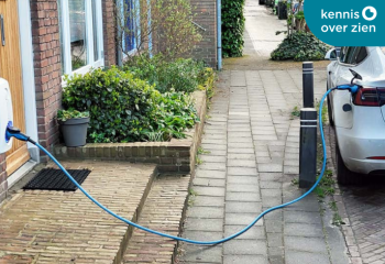 Losliggende oplaadkabel voor elektrische auto op stoep.