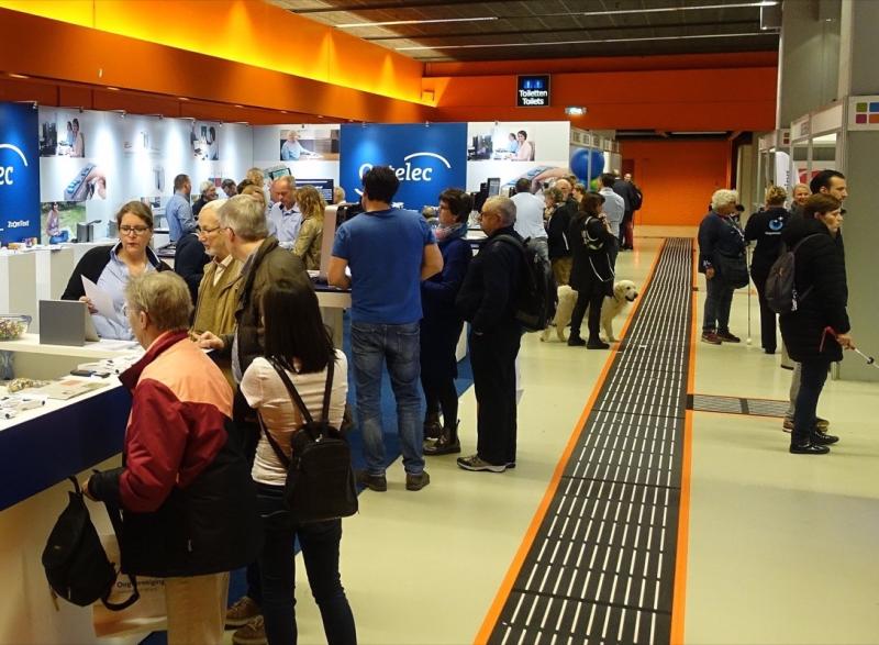 Sfeerimpressie van beurs met stands, geleidelijnen en bezoekers