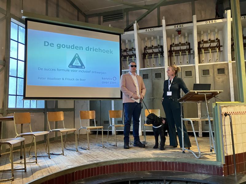 Frouck de Boer en Peter Waalboer geven een presentatie over de Gouden Driehoek. Ze staan op een podium voor een beamer met powerpoint slides. 