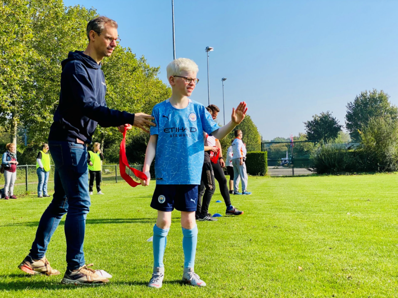 Foto van een trainer en kind op een sportveld