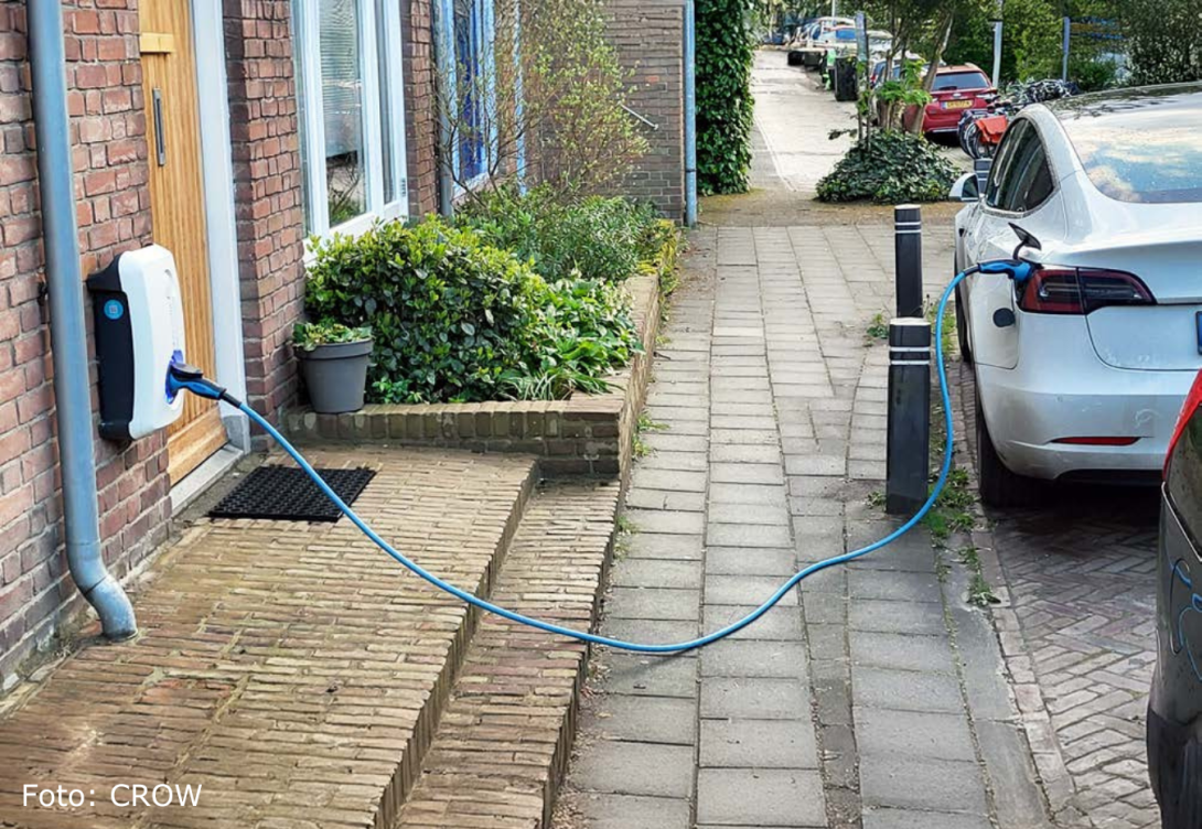Foto van een laadkabel die over de stoep loopt